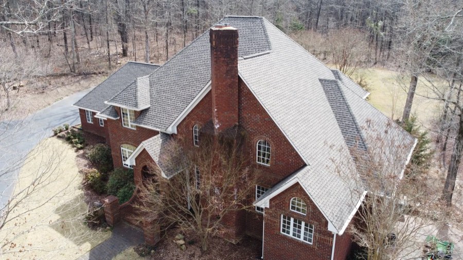 Completed shingle roof on a brick Tudor-style home, aerial view